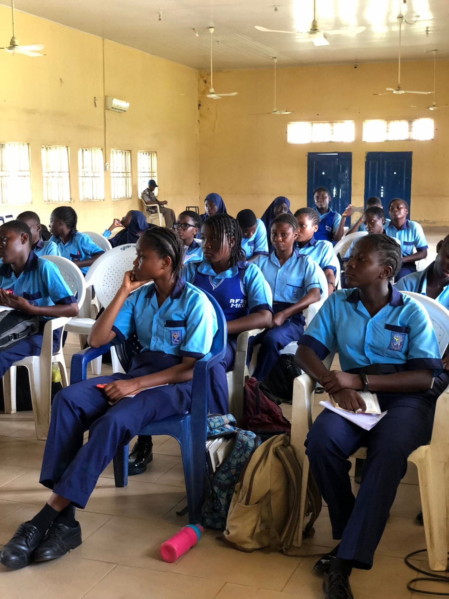 Students in blue uniforms seated in rows listening attentively