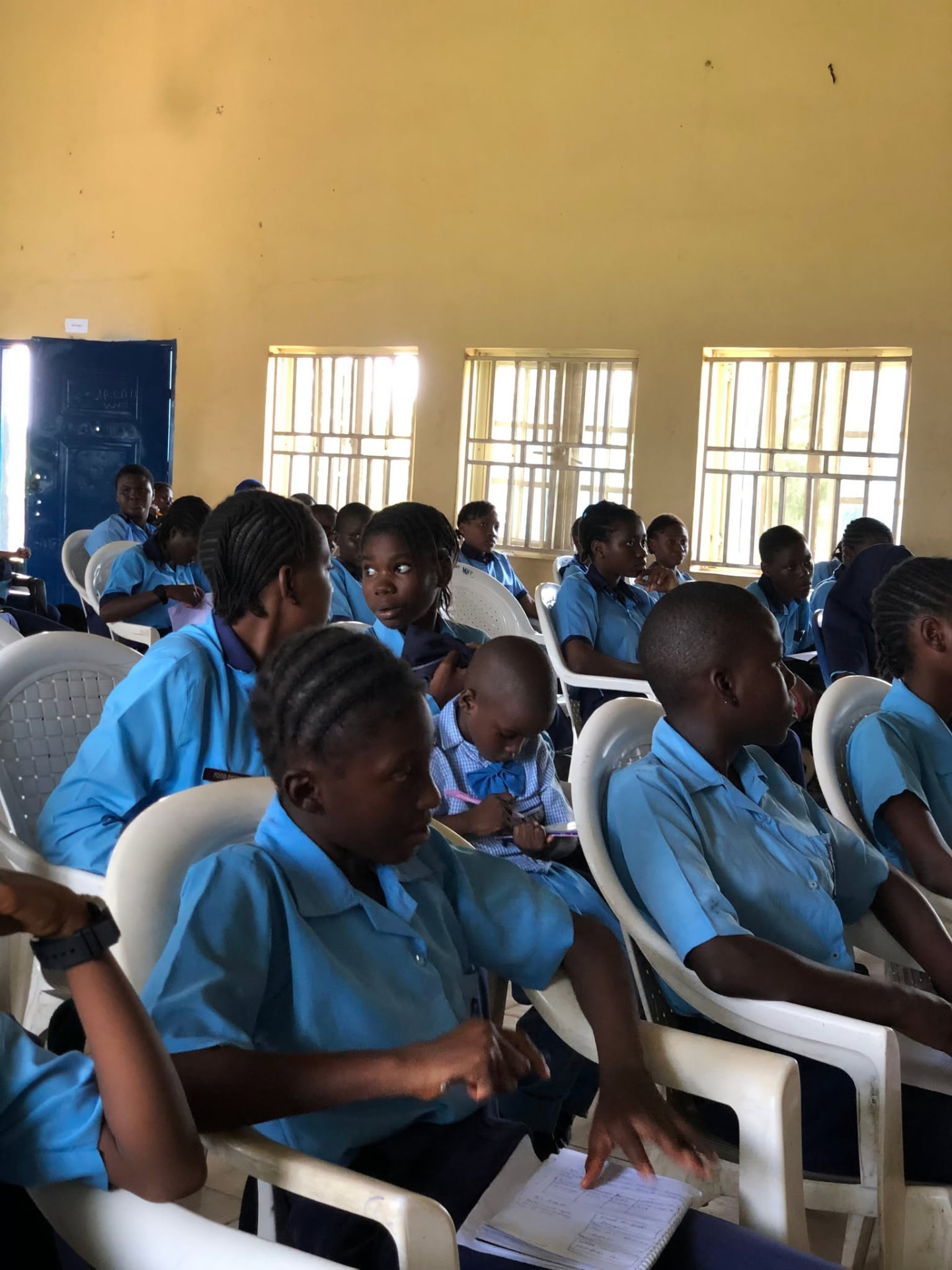 Wide shot of 50 girls seated in the assembly hall during the workshop